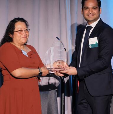 Magnolia Alvarez Velasquez accepts an award from Vikram Swaruup